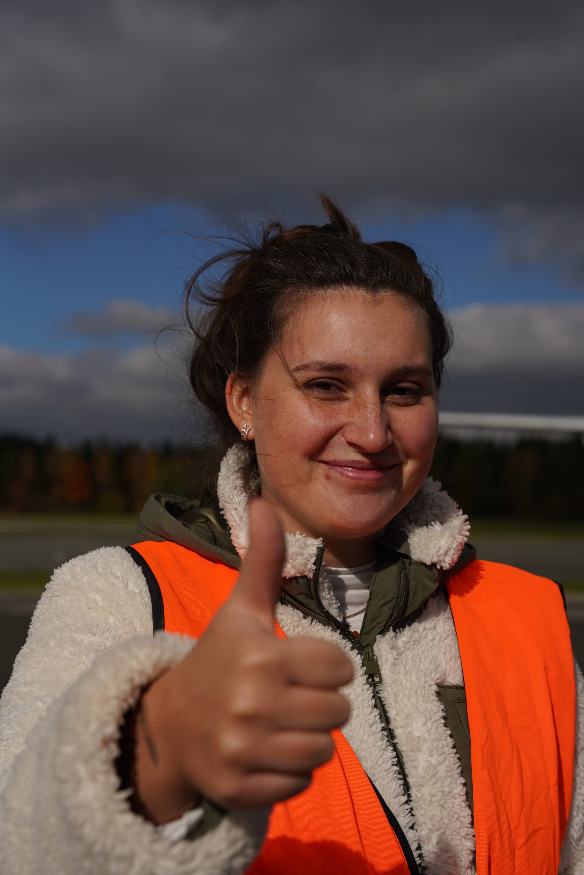 Teammitglied in Warnweste zeigt beim Testing am Flughafen Hof den Daumen hoch und lächelt.