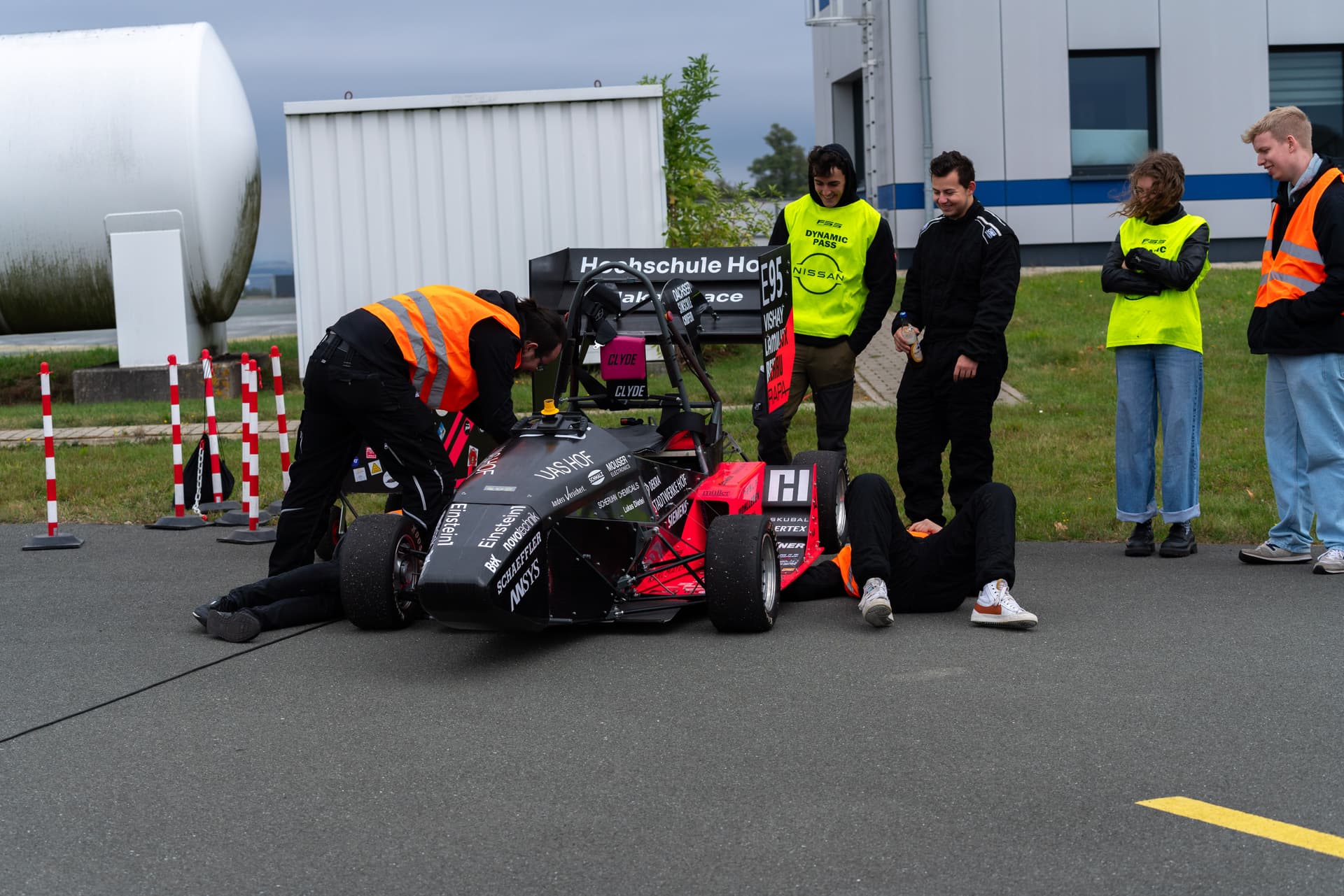 Rennwagen Artemis von vorne, umgeben von sieben Teammitgliedern beim Testing. Drei Mitglieder arbeiten am Wagen, während die vier anderen lächelnd zusehen.